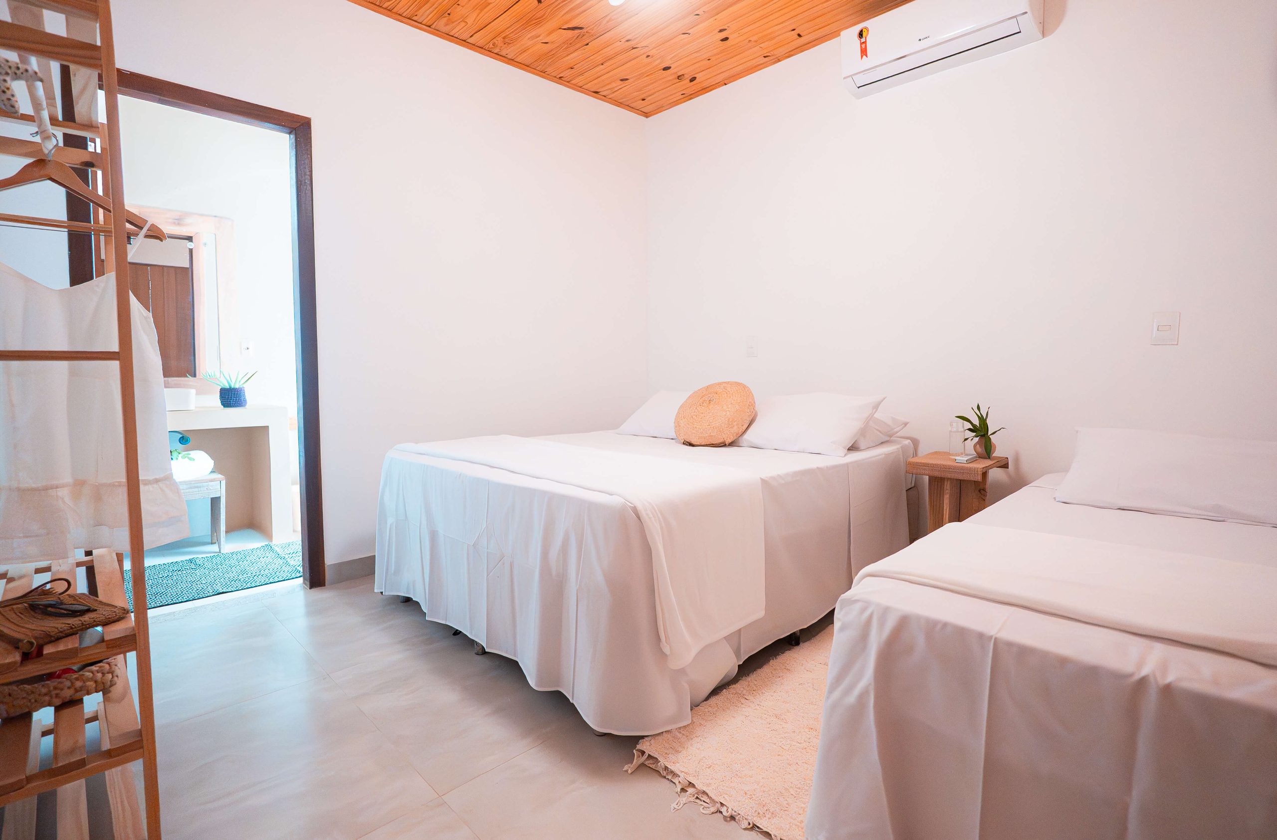 Quarto da Casa Orybá com duas camas e enxoval claro